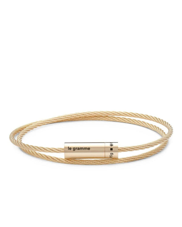 Gold cable bracelet with a cylindrical tag on a white background