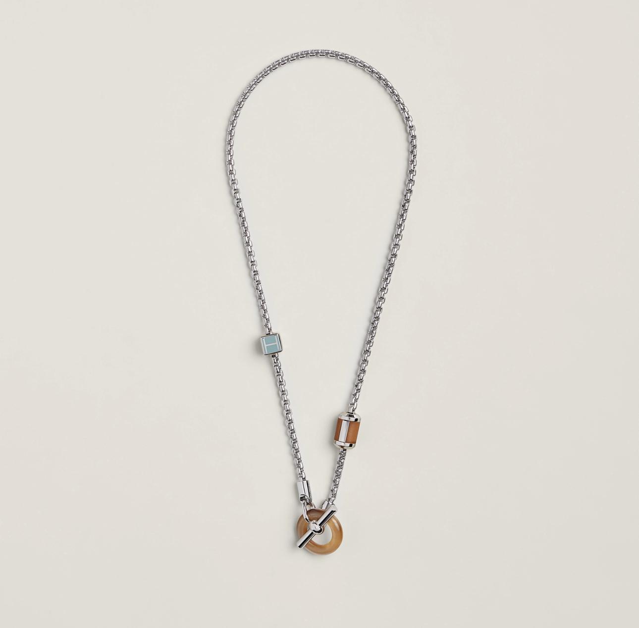 Necklace with wooden pendant and metal chain on a light gray background