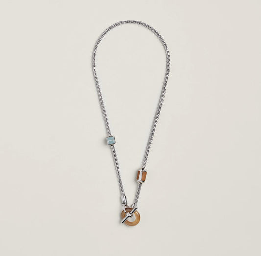 Necklace with wooden pendant and metal chain on a light gray background