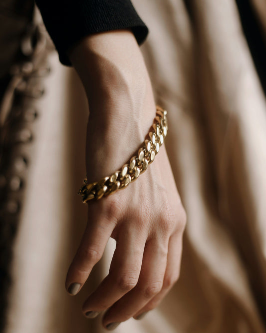 Hand wearing a gold bracelet with a soft focus background