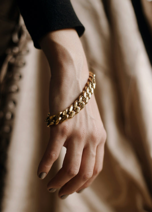 Hand wearing a gold bracelet with a soft focus background