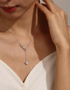 Close-up of a woman wearing a silver necklace with an infinity symbol and heart pendant.