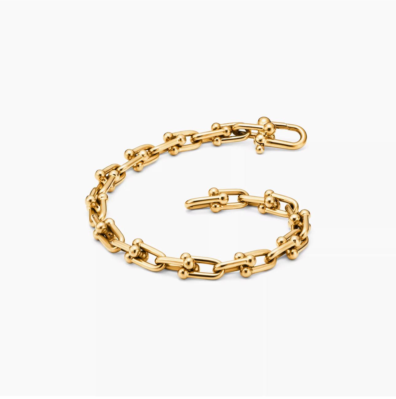 Gold horsebit link chain bracelet on a white background.push-in clasp mechanism