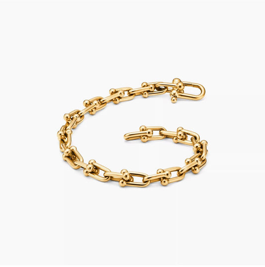 Gold horsebit link chain bracelet on a white background.push-in clasp mechanism