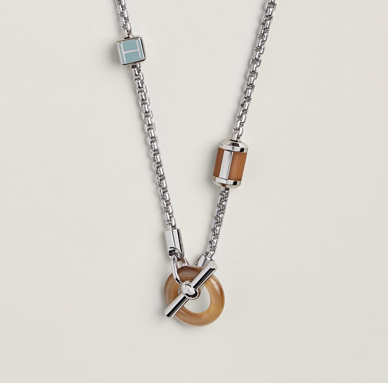 Necklace with wooden and metal pendant on a light beige background