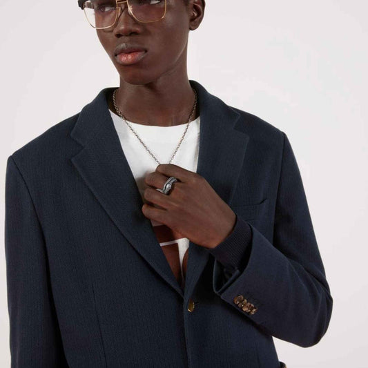 Person wearing a silver snake-shaped ring with a plain background