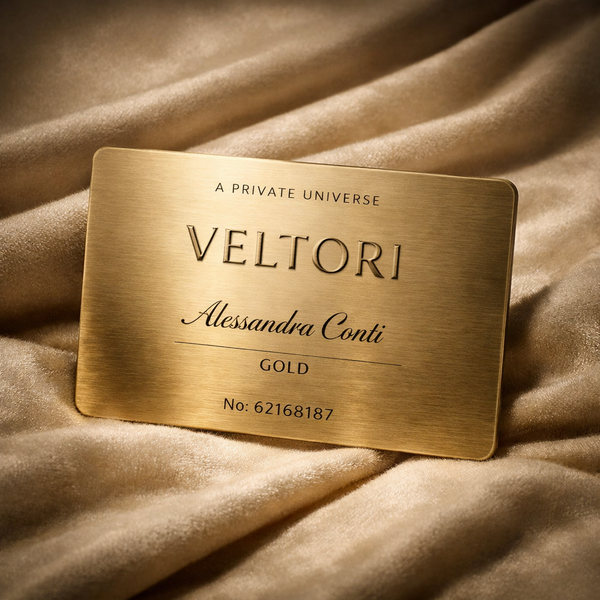 Veltori Gold Membership metal card in brushed champagne gold on a luxurious beige velvet background