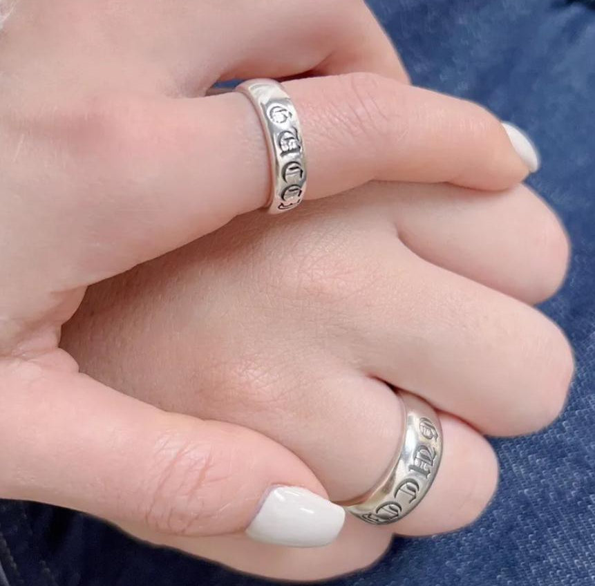 Close-up of hands wearing silver rings with a blurred background