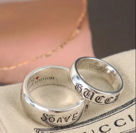 Two silver Gucci rings on a Gucci branded cloth with TL Studio branding at the top.
