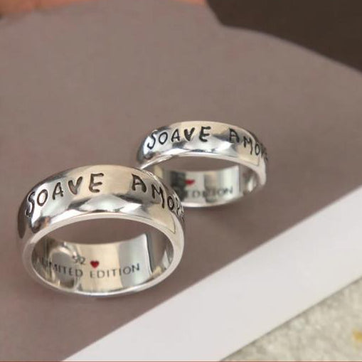 Two silver rings with engraved text on a gray surface