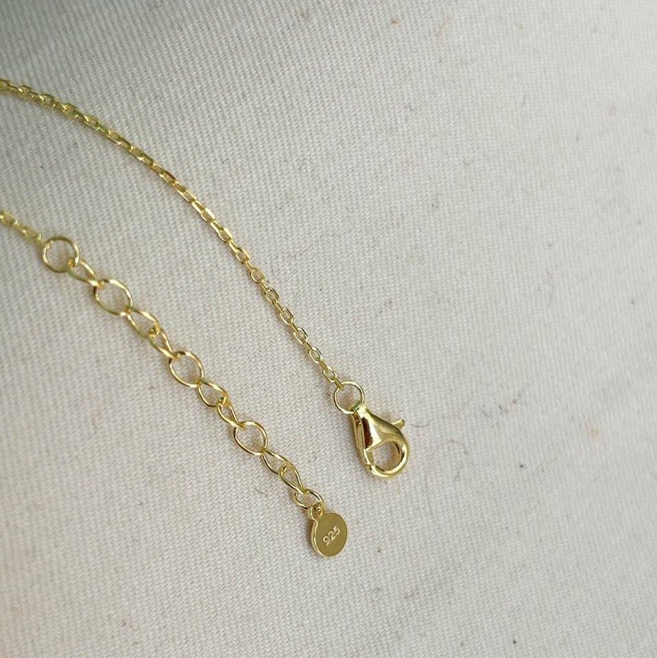 Gold bracelet with a clasp on a light gray background