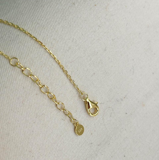 Gold bracelet with a clasp on a light gray background