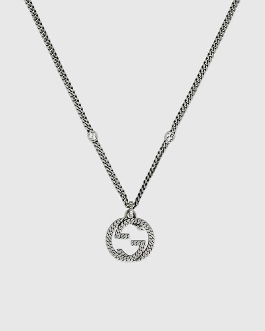Close-up detail of the sculpted interlocking monogram charm with a twisted rope motif and antiqued oxidized finish.