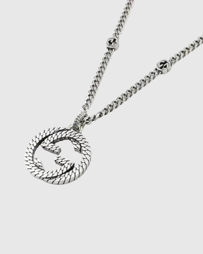 Close-up detail of the sculpted interlocking monogram charm with a twisted rope motif and antiqued oxidized finish.
