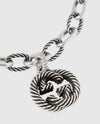 Close-up detail of the sculpted interlocking monogram charm with a twisted rope motif and antiqued oxidized finish.