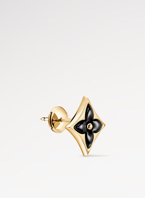 Gold and black Star Ear Stud on a light gray background