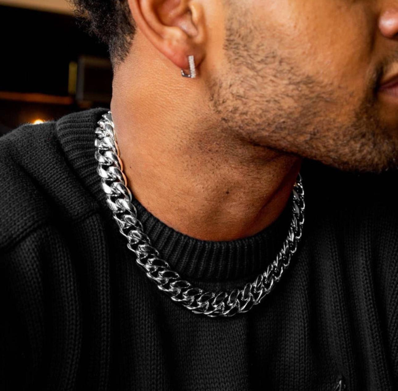 Close-up of a person wearing a silver chain necklace and earring.