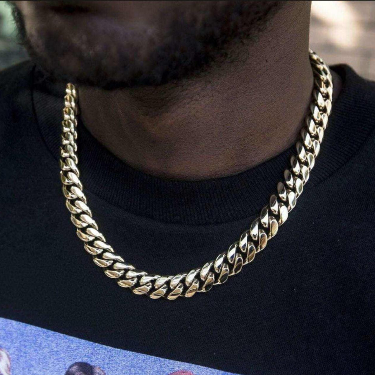 Gold chain necklace worn by a person on a dark background