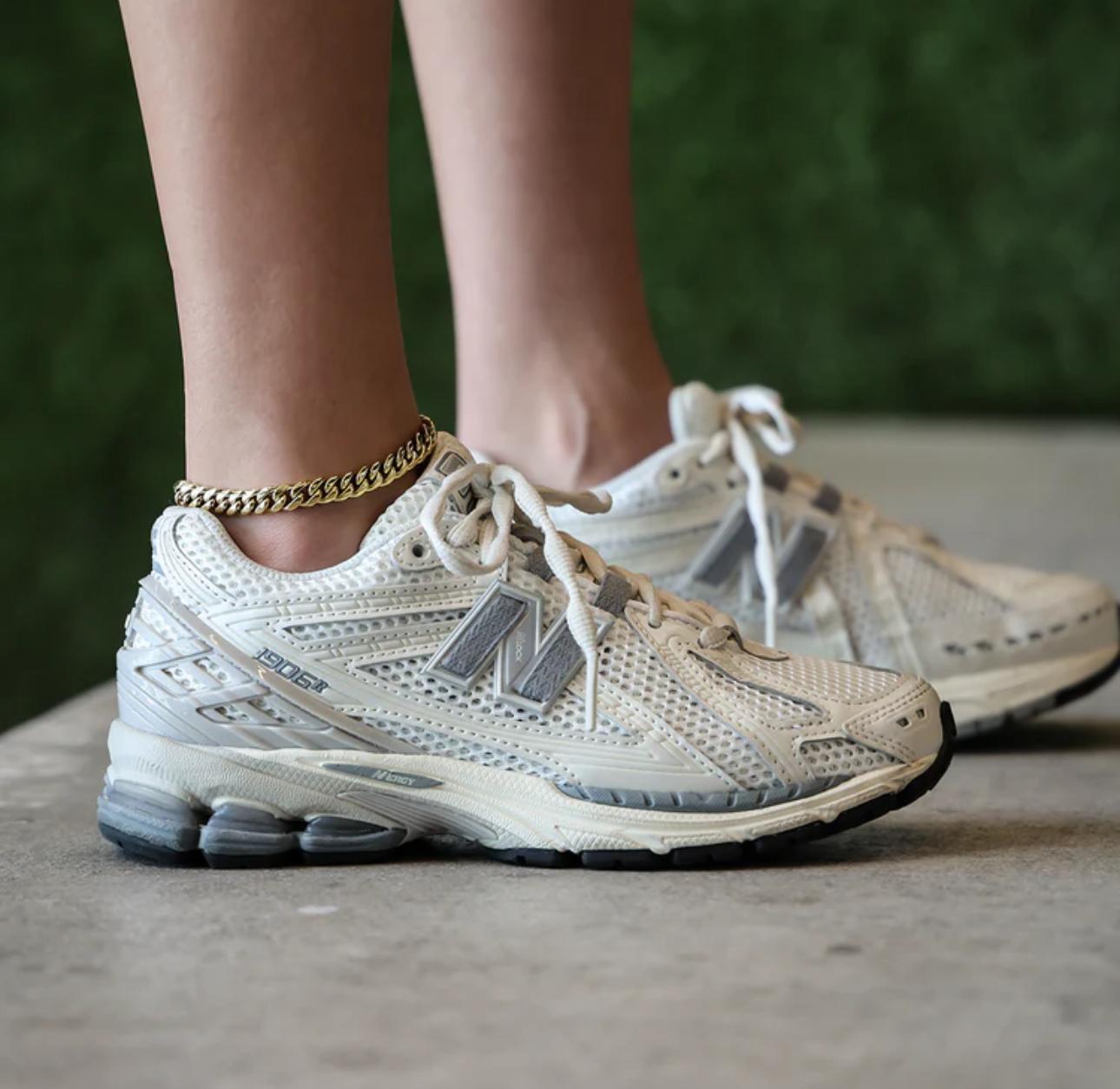 Close-up of a person wearing a gold Cuban Link Anklet with a blurred background