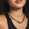 Close-up of a person wearing a gold cuban link necklace with a blurred background