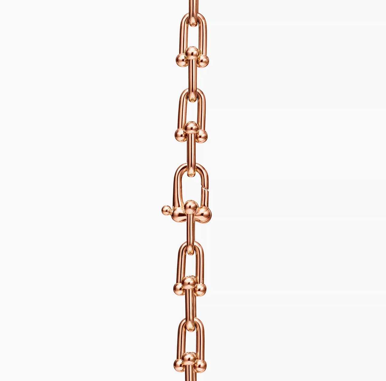 Close-up of a rose gold horseshoe-link chain showing the hidden push-lock clasp integrated within the rounded links.