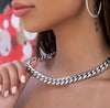 Close-up of a person wearing a silver cuban link necklace with a blurred background
