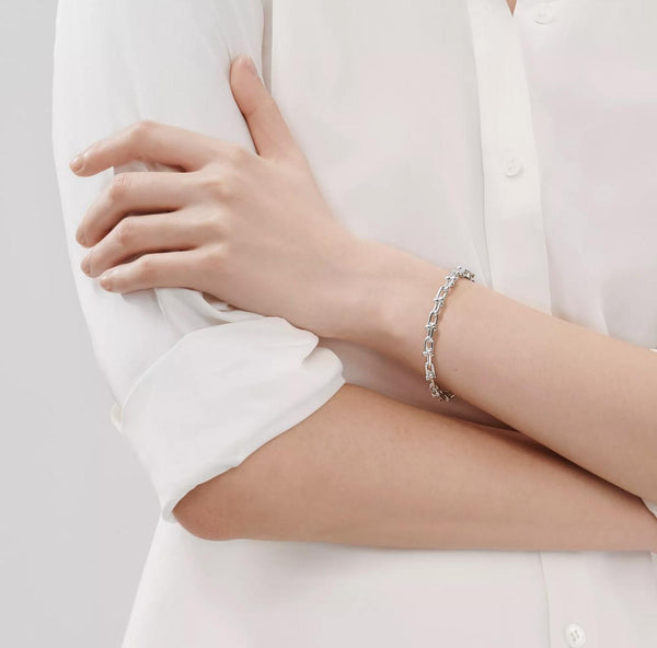 Person wearing a silver bracelet on a plain background