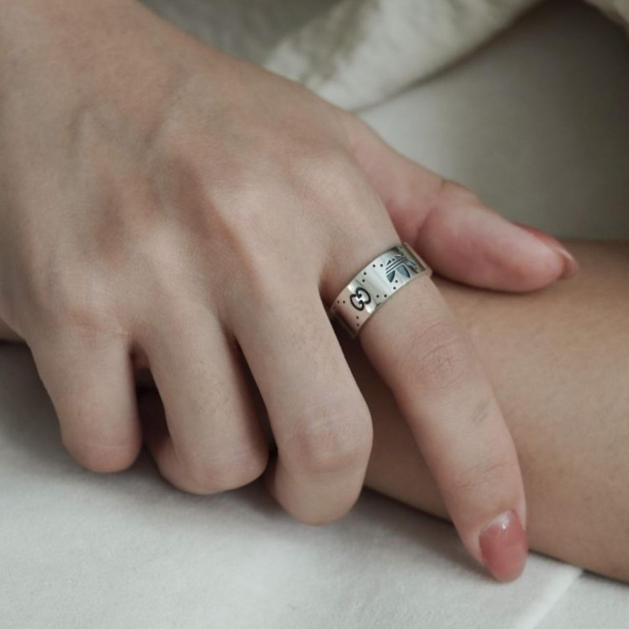 Close-up of a hand wearing a silver ring on a neutral background