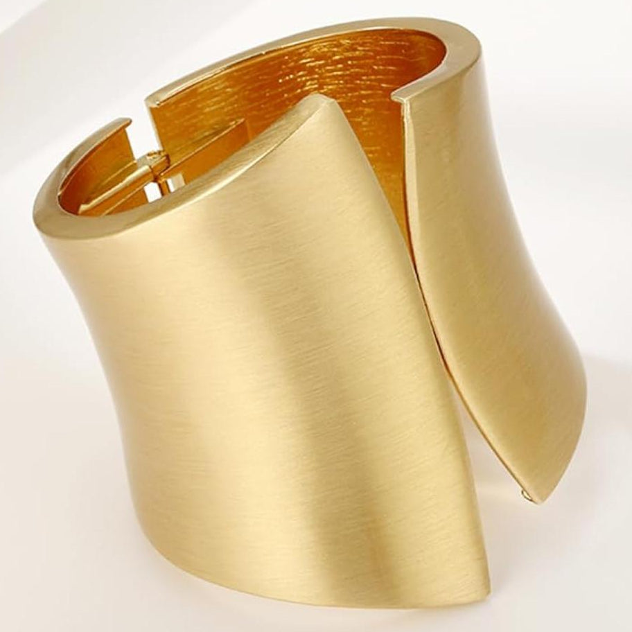 Gold cuff bracelet on a white background