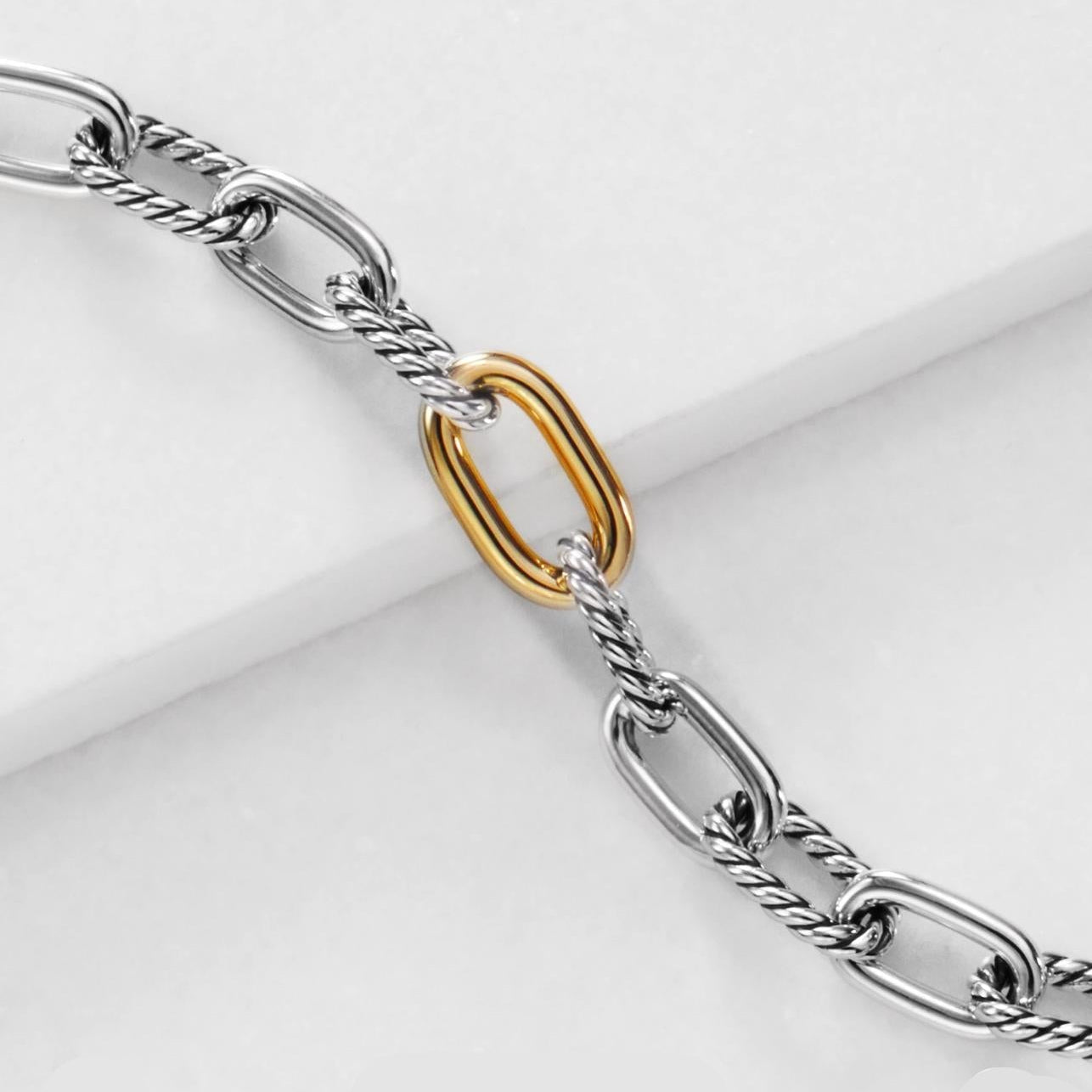 Silver chain bracelet with a gold clasp on a white background