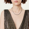Necklace worn by a person in a textured dress against a neutral background