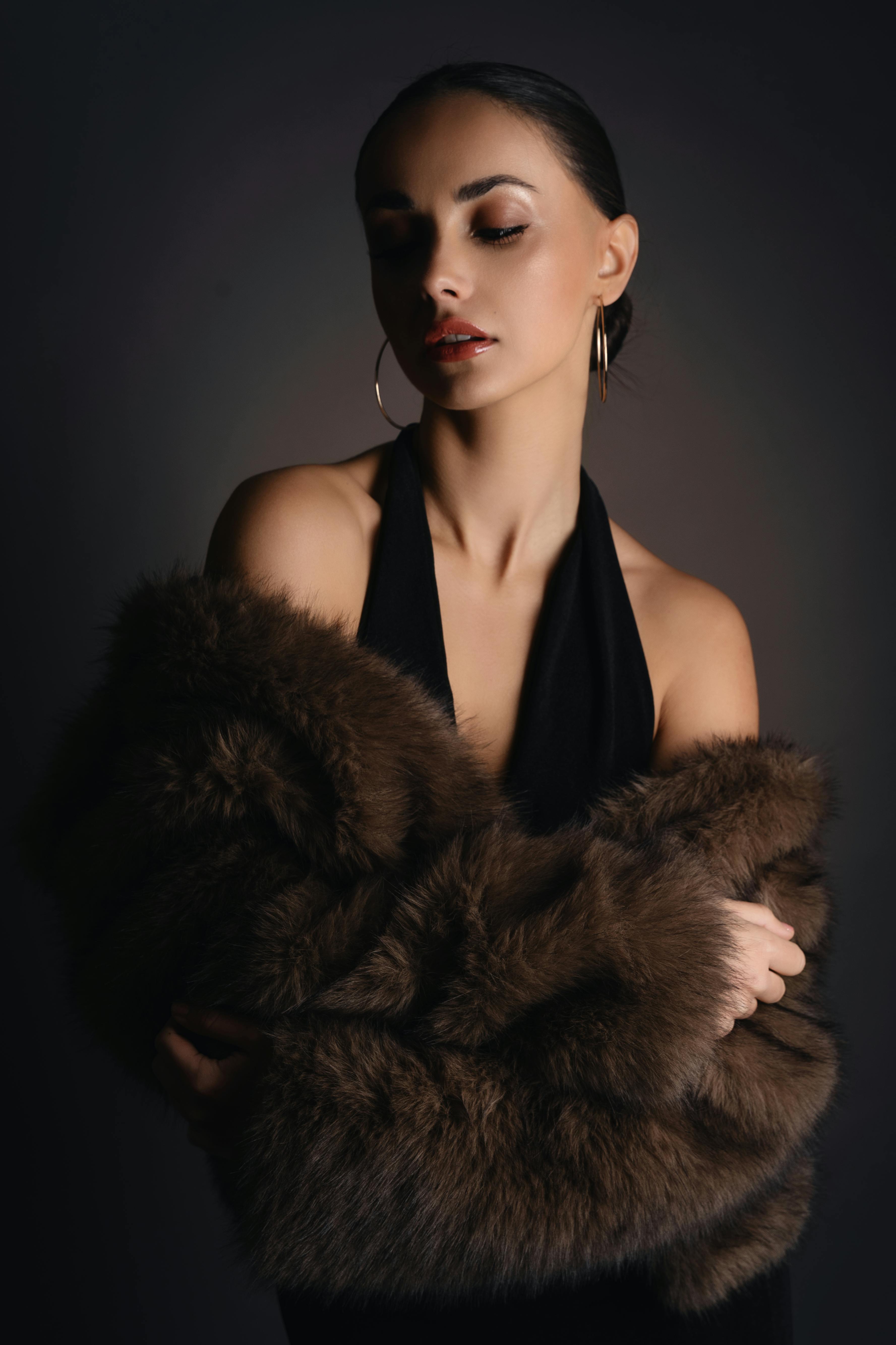 Woman holding a brown fur coat against a dark background