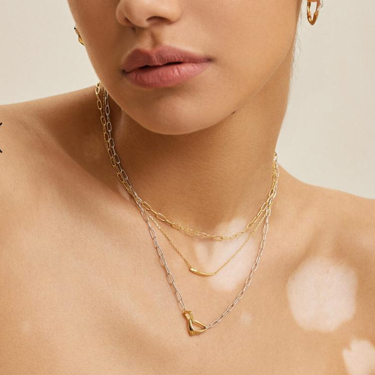 Woman wearing gold necklaces and earrings on a beige background