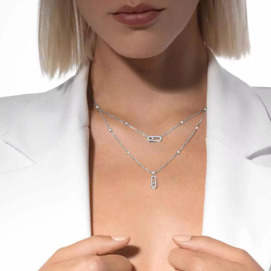Person wearing a silver necklace with a plain background