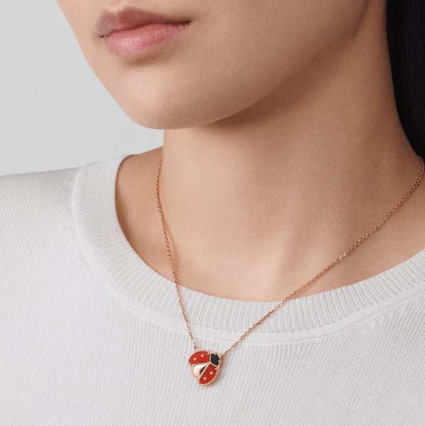 Necklace with a ladybug pendant worn by a person on a plain background