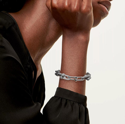 Silver bracelet on a person's wrist with a neutral background