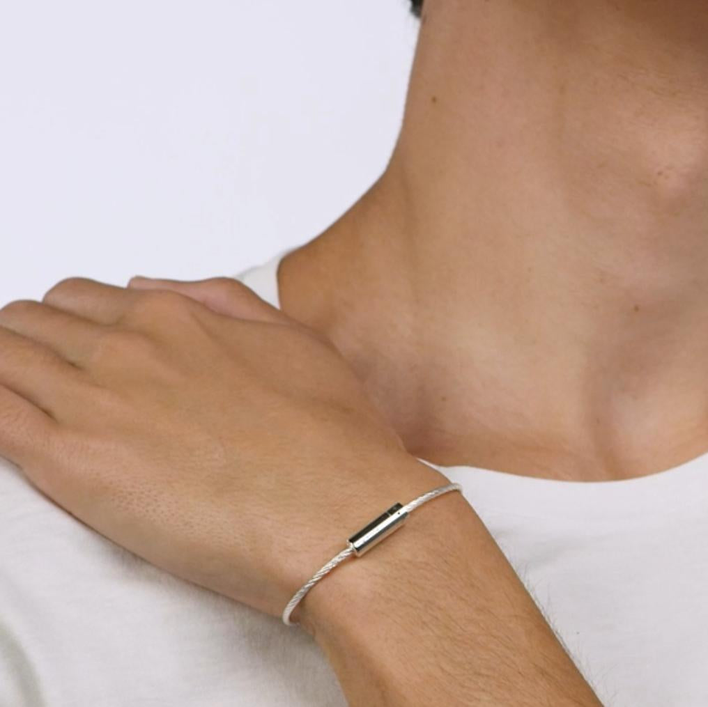 Silver bracelet on a wrist with a plain background