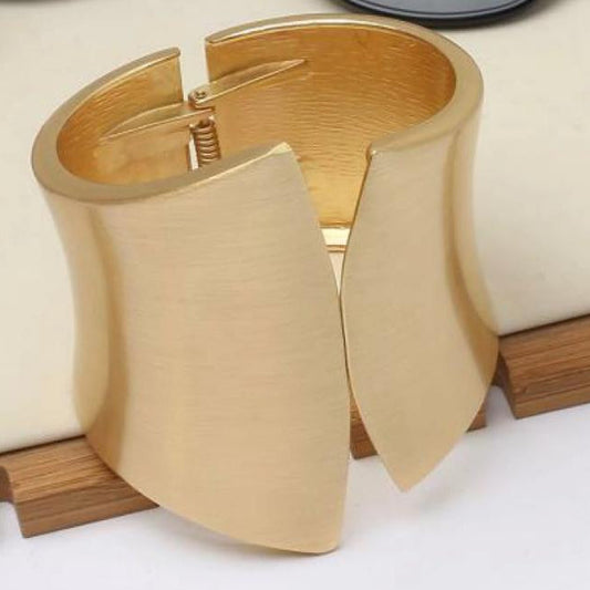 Gold bracelet on a white surface in the background