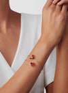Close-up of a wrist wearing a delicate bracelet with ladybug charms against a white background