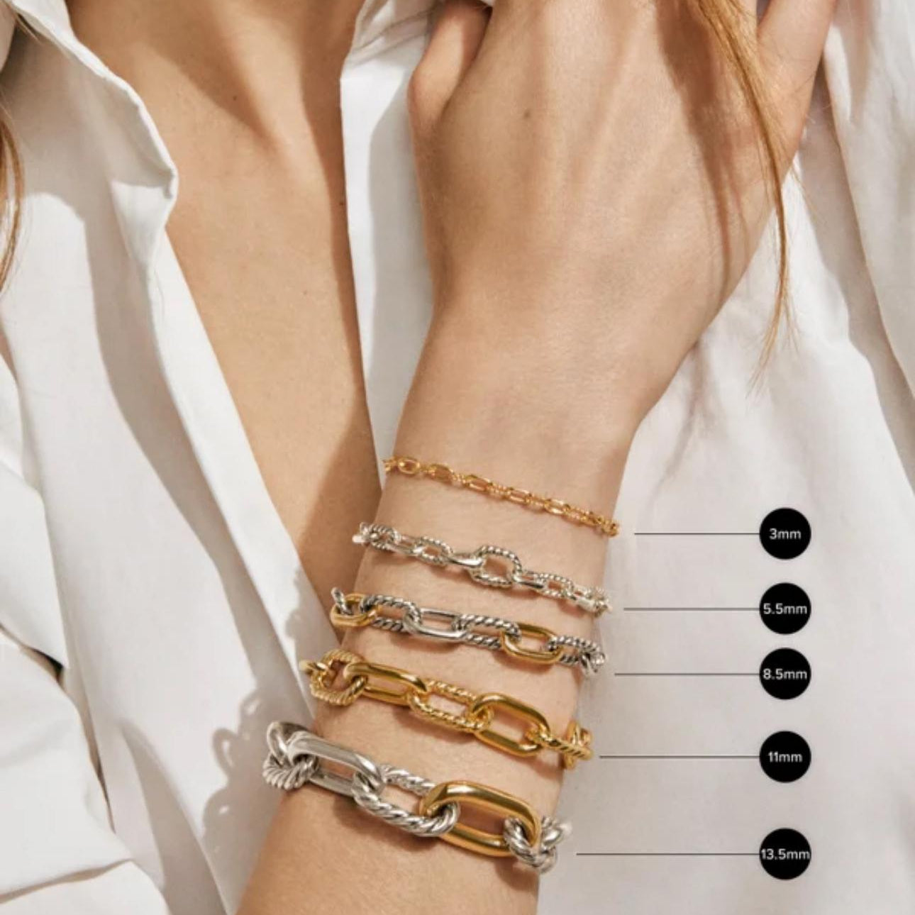 Close-up of a person's wrist wearing multiple gold and silver bracelets on a white background