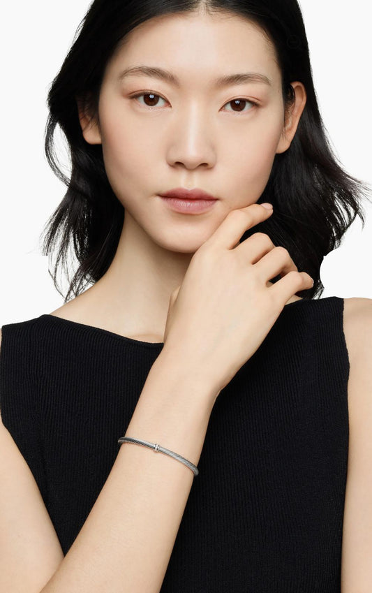 Woman wearing a Sterling silver twisted cable cuff bracelet with a central pavé-accented ring on a white background