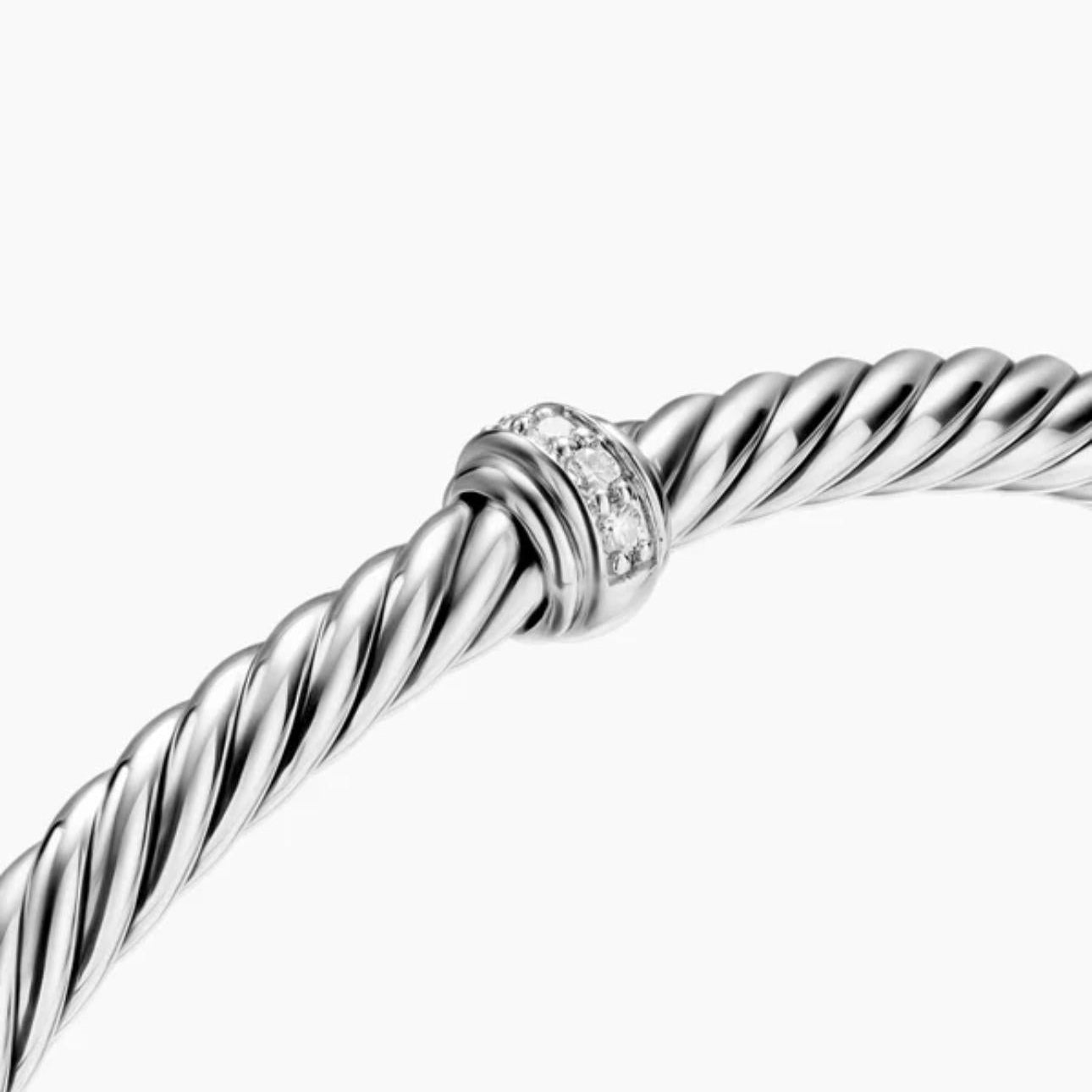 Close-up of a twisted sterling silver cable bracelet featuring a central pavé-set ring.