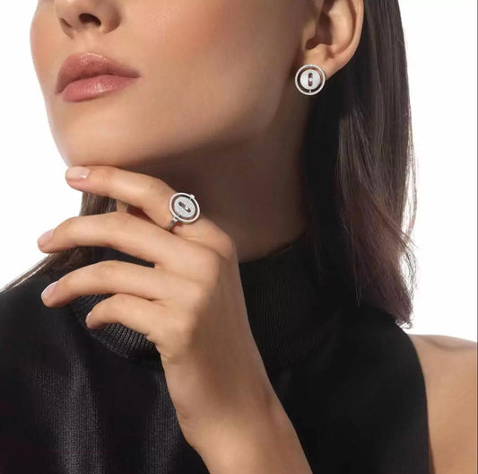 Close-up of a woman wearing a black sleeveless top and silver earrings with a white background