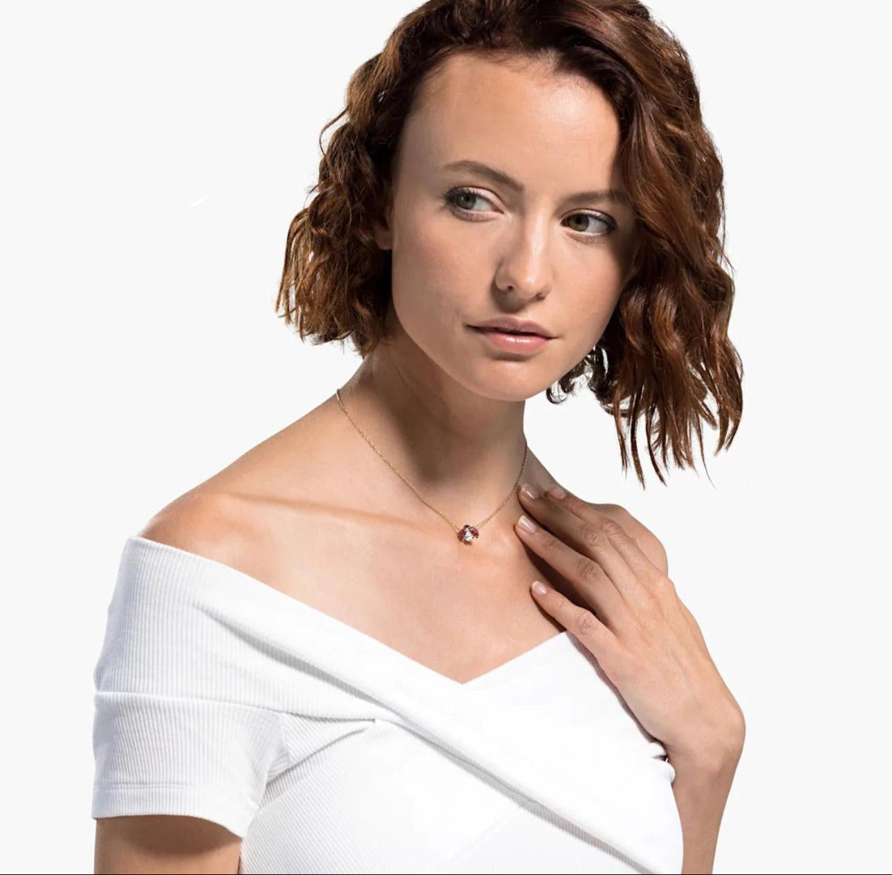 Woman wearing a necklace with a ladybug motif, featuring a central zircon stone and red and white accents on a gold-tone finish. on a plain background