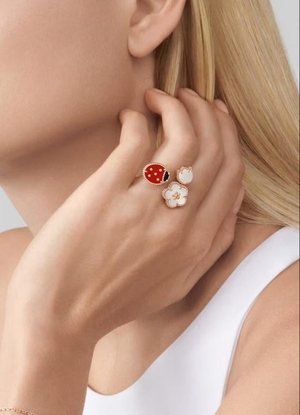 Woman wearing a bracelet and earrings with ladybug designs on a neutral background