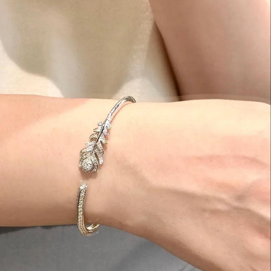 Silver bracelet with leaf design on a wrist against a neutral background