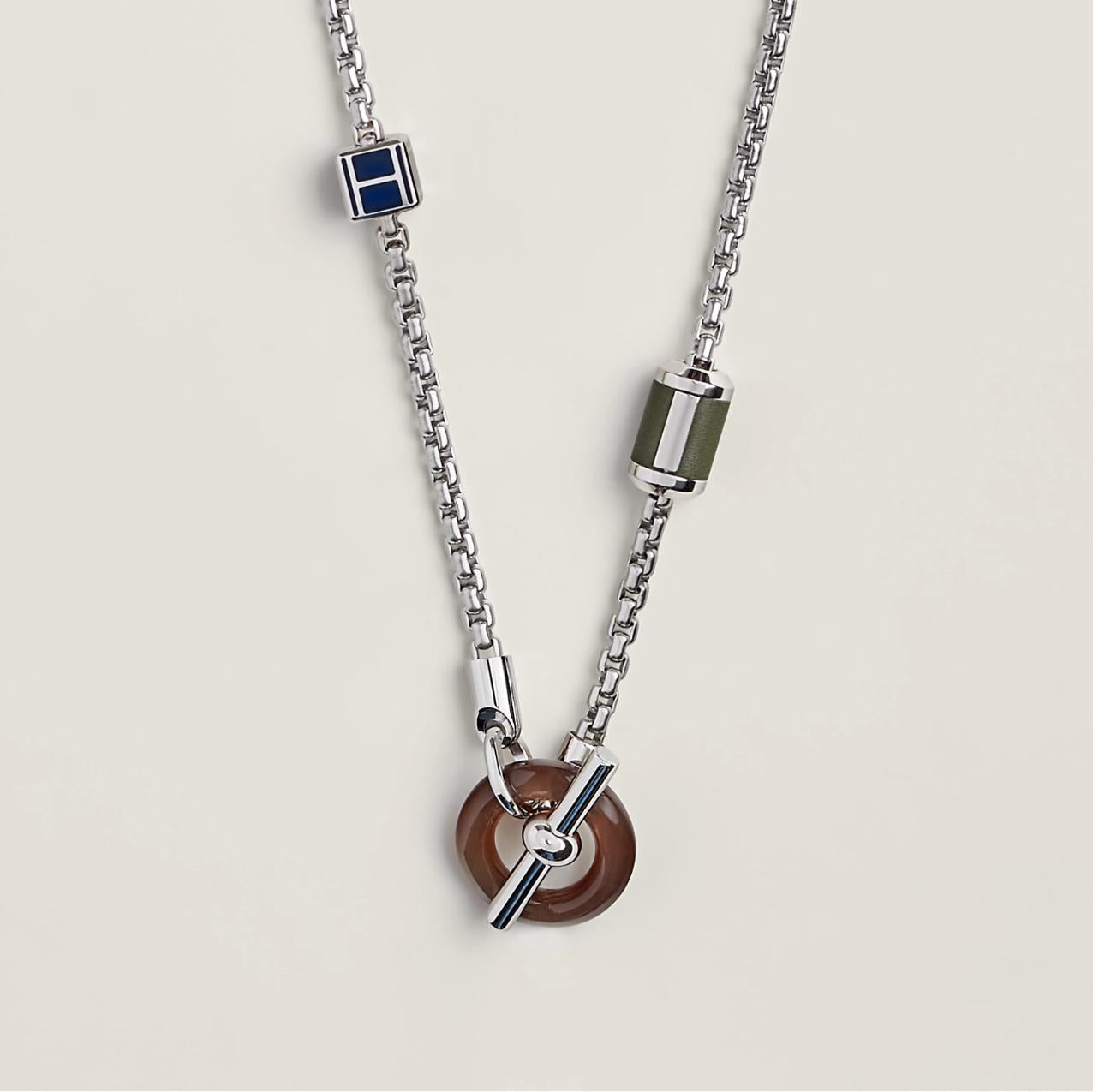 Silver chain necklace with various pendants on a light gray background