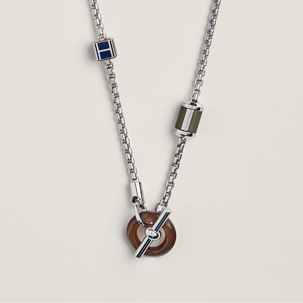 Silver chain necklace with various pendants on a light gray background