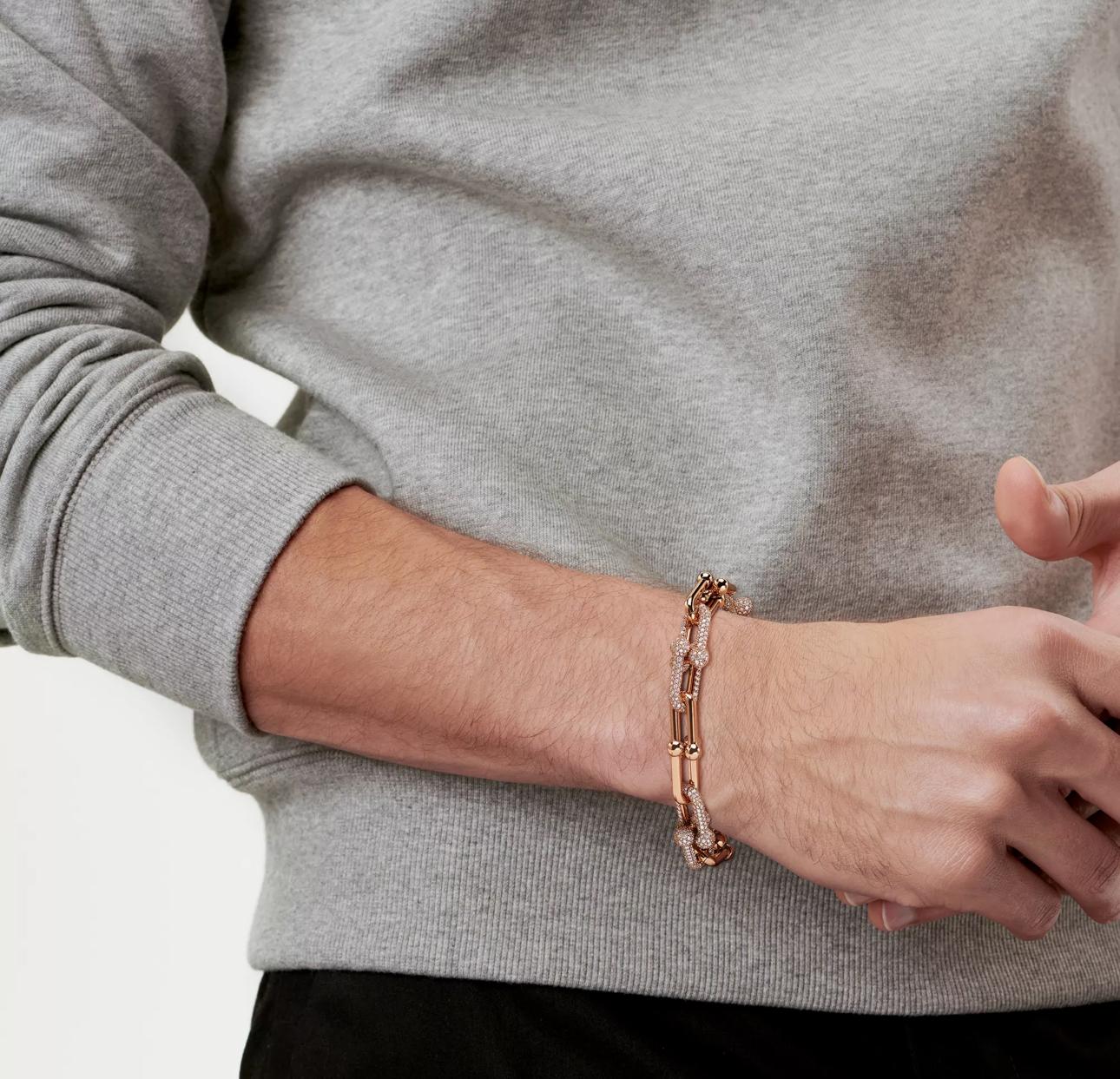 Person wearing a rose gold bracelet on a neutral background