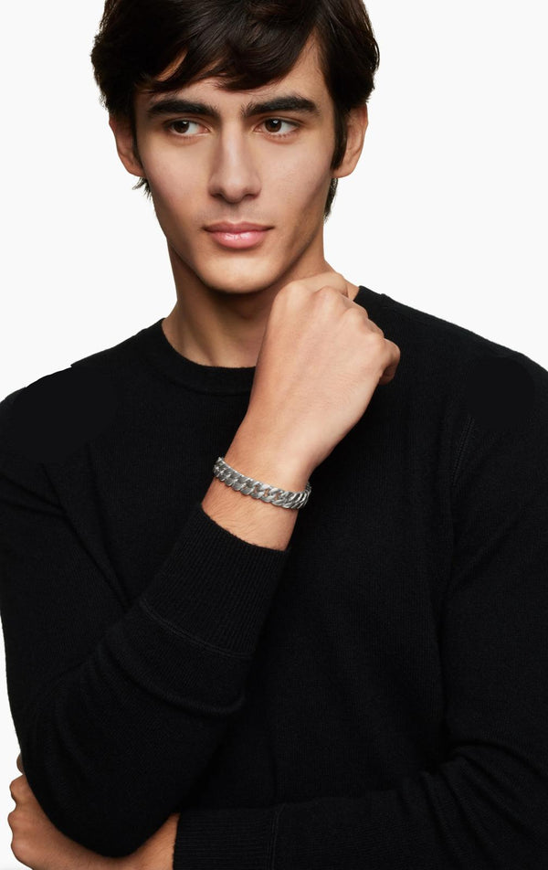 Man wearing a black sweater with a silver bracelet on a white background